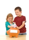 Grinning kids stuffing piggy bank Royalty Free Stock Photo