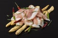 Grissini bread sticks with prosciutto on a wooden board with red and green pepper Royalty Free Stock Photo