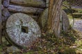 Gristmill stones leaned up against a log structure Royalty Free Stock Photo