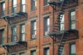 Gritty exterior of orange brick  tenement style apartment building with black fire escapes in central Manhattan, New York City Royalty Free Stock Photo