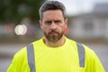 Grizzled man portrait. Worker man. Serious man wearing yellow safety vest. Unshaven man face