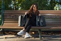 Grl with paper shopping bags rests on bench in park and enjoys shopping. Successful shopping