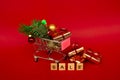 Grocery basket with golden gift boxes and Christmas balls, a sprig of Christmas tree and English letters SALE on a red background
