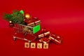 Grocery basket with golden gift boxes and Christmas balls, a sprig of Christmas tree and English letters SALE on a red background