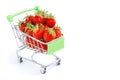Grocery cart with strawberries on a white background. Strawberries in a small trolley from a super market. Fresh red strawberries Royalty Free Stock Photo