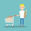 Grocery shopping concept: Young customer standing with a trolley Royalty Free Stock Photo