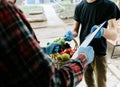 A grocery store delivery man wearing a black polo-shirt delivering food to an old man at home