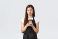 Grocery store employees, small business and coffee shops concept. Gloomy and upset cute female barista looking left Royalty Free Stock Photo