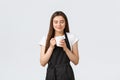 Grocery store employees, small business and coffee shops concept. Pleased cute saleswoman in black apron close eyes and