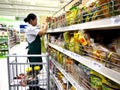 A grocery store worker refills the shelves with new stocks of different kinds of food.