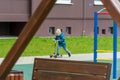 Grodno, Belarus April 1, 2023: A child in a jacket and blue jeans rides a scooter on the sidewalk in the yard. The concept of