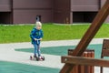 Grodno, Belarus April 1, 2023: A child in a jacket and blue jeans rides a scooter on the sidewalk in the yard. The concept of
