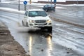 Grodno, Belarus, February 9, 2022: Motion of the car in the rain on a large puddle, splashes of water and wet snow from the wheels