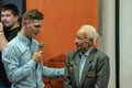 Grodno, Belarus, January 16, 2019: A young reporter holding a microphone. Conversation with an elderly man on stage. The retiree