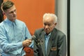 Grodno, Belarus, January 16, 2019: A young reporter holding a microphone. Conversation with an elderly man on stage. The retiree