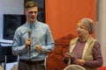 Grodno, Belarus, January 16, 2019: A young reporter holding a microphone. Conversation with an elderly man on stage. The retiree