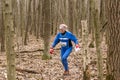 Cute elderly caucasian women wearing sportswear running through a forest