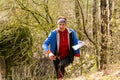 Cute elderly caucasian women wearing sportswear running through a forest