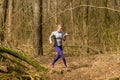 Strong caucasian young woman wearing sportswear running through a forest