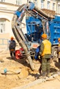 Workers use a suction excavator based on a MAN truck to sample soil in a well for communications