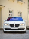 Modern luxury BMW 750Li XDrive car front view parked on stone paved parking near ancient house vertical