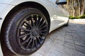 Modern luxury BMW 750Li XDrive car parked on stone paved parking with Mansory black alloy wheels and Falken tires close-up