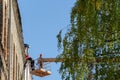 Grodno, Belarus, October 11, 2018: Two builders repairing the roof of a old brick building. People on the crane platform. Crane on