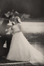 Gromm kisses bride's cheek standing on the lake's shore Royalty Free Stock Photo