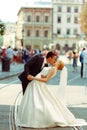 Groom bends bride over kissing her on a city square Royalty Free Stock Photo