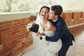 Groom bites bride's cheeck hugging her from behind Royalty Free Stock Photo