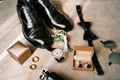 Groom black leather shoes lie on the table next to the wedding rings, boutonniere and watch