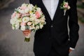 Groom in a black suit with boutonniere holding a wedding bouquet Royalty Free Stock Photo