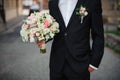 Groom in a black suit holding a gentle wedding bouquet