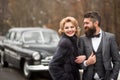 Groom in a black suit with woman outdoor near retro car. Romantic date. Vintage people. Royalty Free Stock Photo