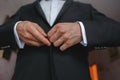 Groom in black tuxedo and bowtie correct his buttons on white shirt. Wedding. Royalty Free Stock Photo