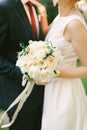 Groom in a blue checkered suit hugs bride in a white dress with a bouquet of flowers. Close-up Royalty Free Stock Photo