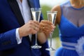 The groom in a blue suit and the bride in a blue dress standing with glasses in which is poured the champagne
