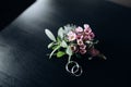 Groom boutonniere and wedding rings on a dark background Royalty Free Stock Photo