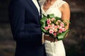 Groom and the bride hold a bouquet from roses