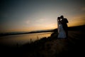 Groom and bride is hugging and kissing on the background beautiful sunset on the lake Royalty Free Stock Photo