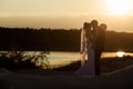 Groom and bride is hugging and kissing on the background beautiful sunset on the lake Royalty Free Stock Photo