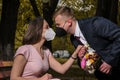 Groom and bride kissing each other in protective medical masks on face in Royalty Free Stock Photo