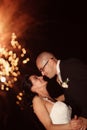 Groom and bride kissing with fireworks in background