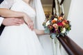 Groom and bride with red rose bouquet hold each other hands on Royalty Free Stock Photo