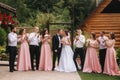 Groom and bride stand with groomsman and bridesmaid outside. Newlyweds kissing and friend clap. Wedding day Royalty Free Stock Photo