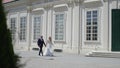 Groom and bride stand on stairs by the great palace in Wiena