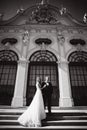 Groom and bride stand on stairs by the great palace in Wiena. Stylish couple