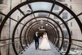 Groom and bride walking in glasses tunnel. Outside is winter