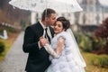 Groom and bride walking in the park on their wedding day. Autumn weather. Rair. Couple umbrella Royalty Free Stock Photo