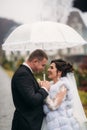 Groom and bride walking in the park on their wedding day. Autumn weather. Rair. Couple umbrella Royalty Free Stock Photo